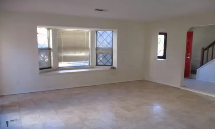 Spare room with stairs, plenty of natural light, and baseboards