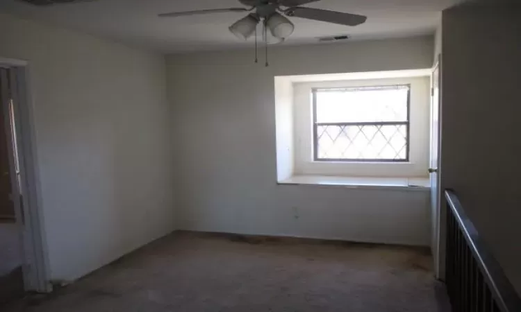 Carpeted empty room featuring radiator, ceiling fan, and visible vents