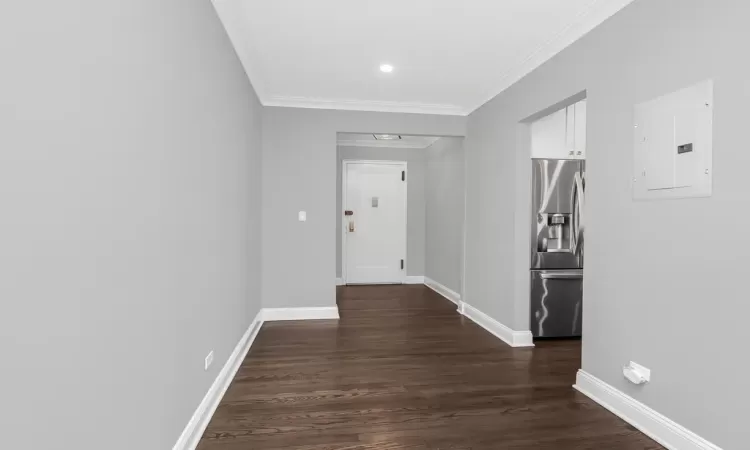 Corridor with electric panel, baseboards, dark wood finished floors, and crown molding