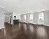 Unfurnished living room featuring dark wood-type flooring, radiator, and crown molding