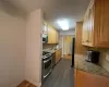 Kitchen with baseboards, decorative backsplash, light stone counters, stainless steel appliances, and a sink