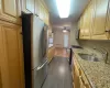 Kitchen with light stone counters, stainless steel appliances, a sink, dark wood-style floors, and tasteful backsplash