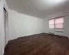 Spare room featuring radiator heating unit, baseboards, and dark wood-type flooring