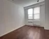 Spare room featuring radiator heating unit, baseboards, and dark wood finished floors