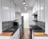 Kitchen with freestanding refrigerator, gas range oven, under cabinet range hood, black microwave, and a sink