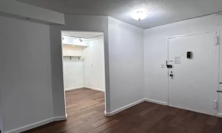 Entrance foyer with dark wood-style floors, a textured ceiling, and baseboards