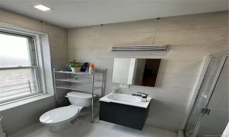 Full bathroom featuring toilet, a shower stall, vanity, and tile patterned floors