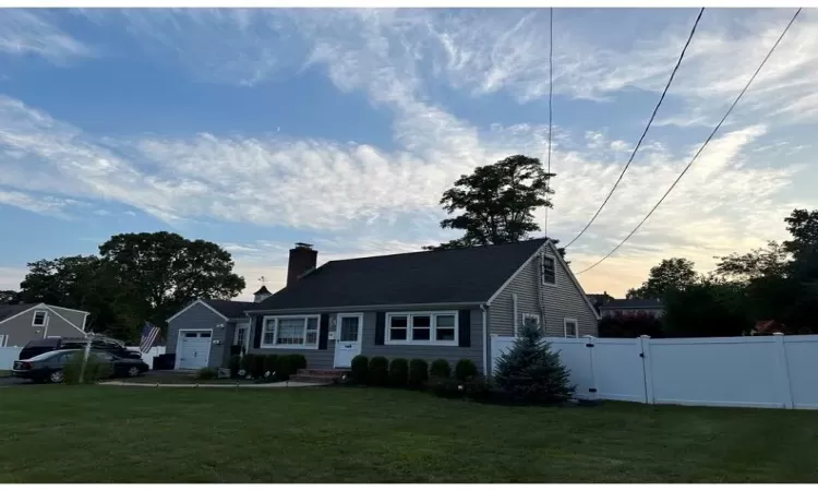 View of front of home featuring fence, concrete driveway, a gate, a chimney, and a front yard