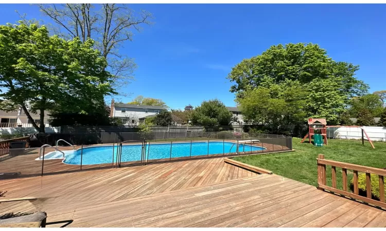 View of swimming pool featuring playground community, a yard, fence, and a fenced in pool