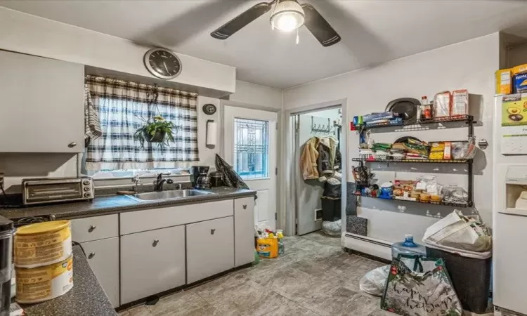 Kitchen featuring ceiling fan, a toaster, a sink, white cabinets, and dark countertops