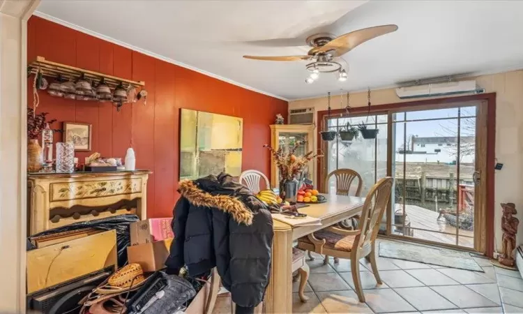 Dining space with light tile patterned floors, ornamental molding, a wall unit AC, and a ceiling fan