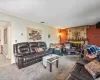 Carpeted living room with a baseboard radiator, visible vents, and a brick fireplace