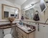 Bathroom with wainscoting, vanity, toilet, and tile walls