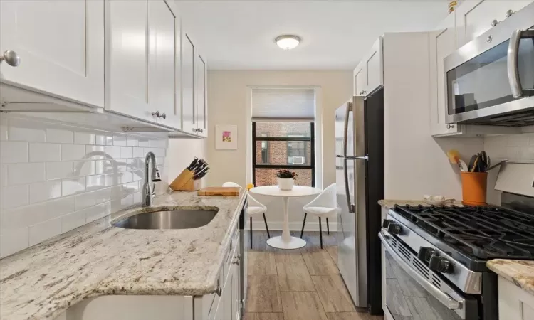 Kitchen featuring stainless steel appliances, backsplash, a sink, and white cabinetry