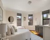 Bedroom featuring multiple windows, baseboards, and wood finished floors