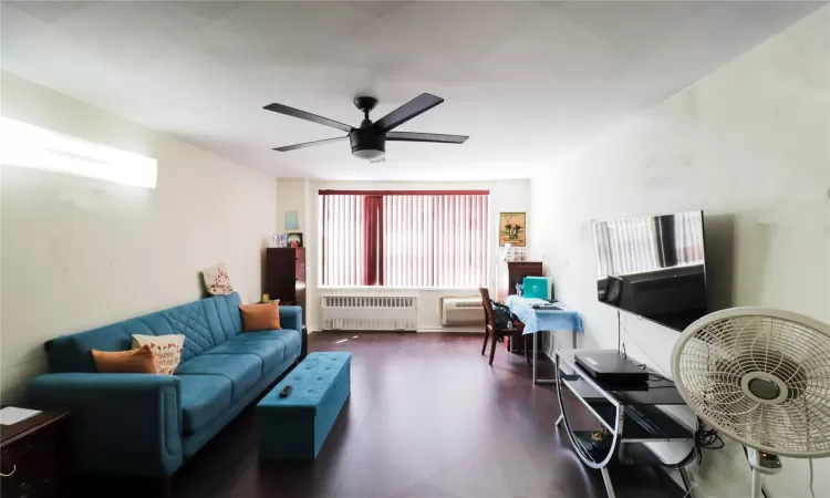 Office area with radiator heating unit, ceiling fan, and wood finished floors