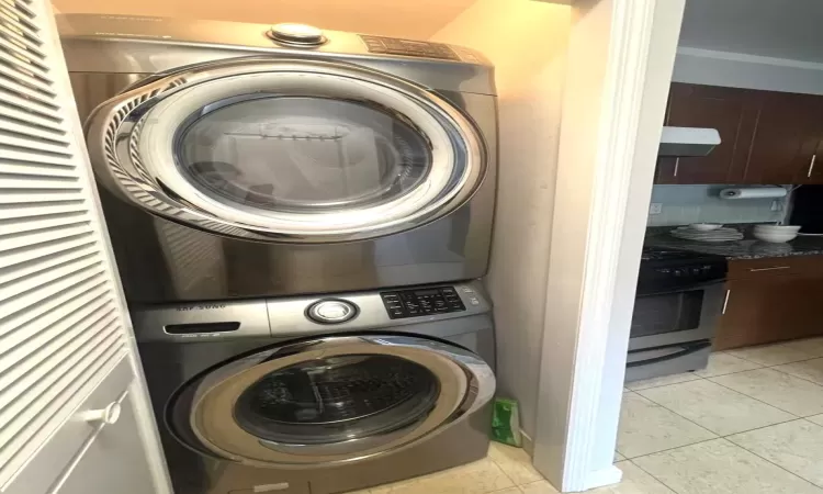 Laundry area featuring light tile patterned floors, laundry area, and stacked washer and dryer