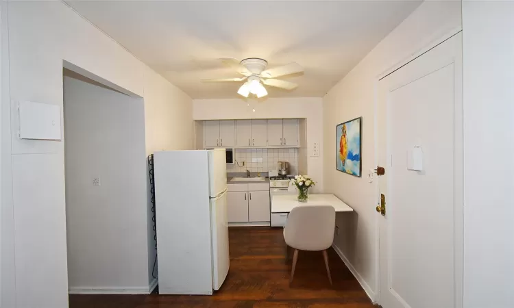 Kitchen featuring white appliances, a sink, light countertops, backsplash, and built in desk