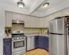 Kitchen featuring blue cabinetry, stainless steel appliances, light countertops, a sink, and under cabinet range hood