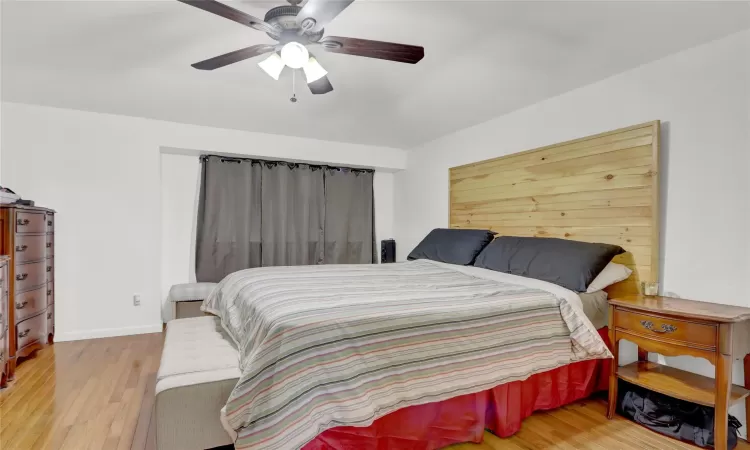 Bedroom featuring ceiling fan, wood finished floors, and baseboards