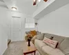 Carpeted living area featuring ceiling fan and baseboards