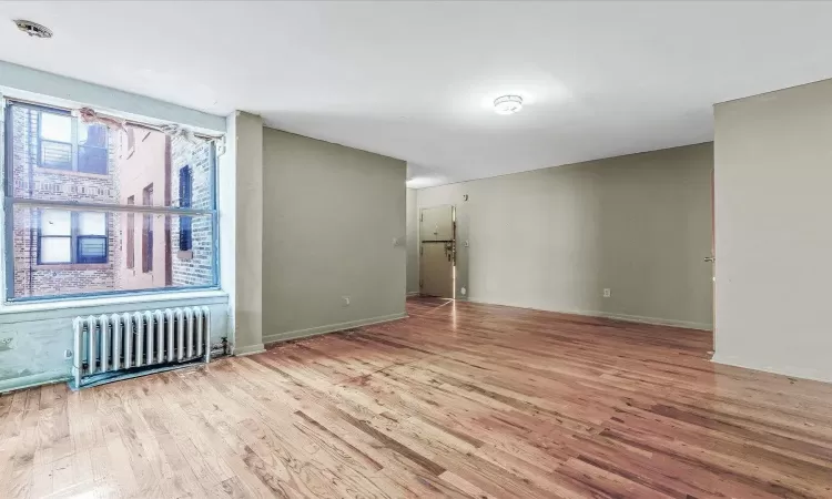 Spare room featuring radiator, baseboards, and wood finished floors