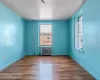 Empty room with baseboards, wood finished floors, a wealth of natural light, and radiator