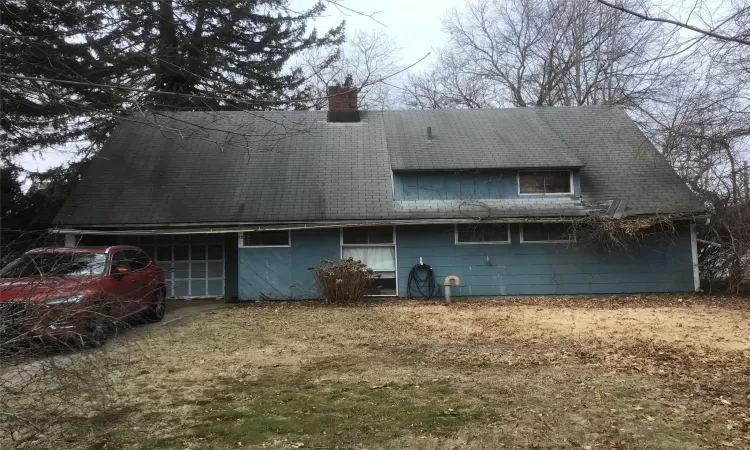 Rear view of house with an attached garage and a chimney