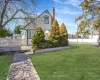 View of front of property featuring a chimney, fence, and a front yard