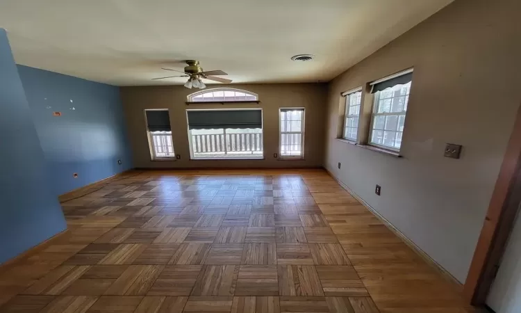 Living room featuring visible vents, a ceiling fan, and baseboards