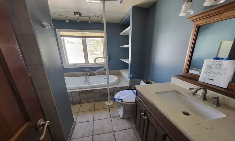 Full bath with a relaxing tiled tub, toilet, separate shower and vanity