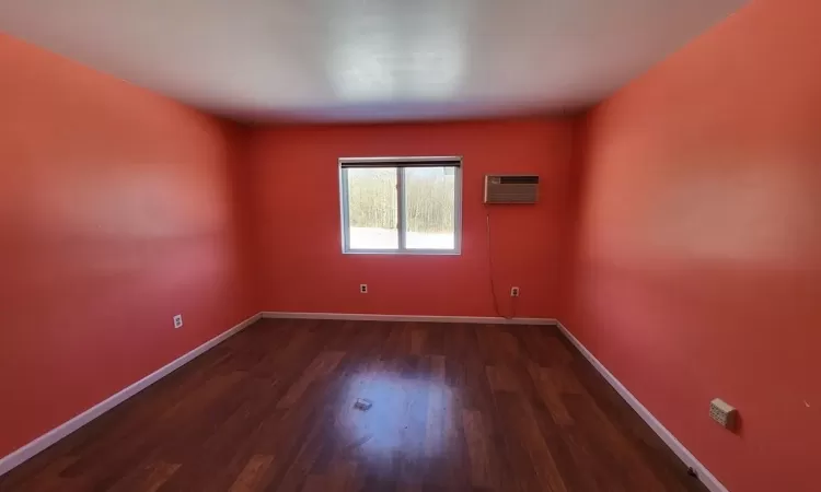 Bedroom with dark wood-type flooring, and baseboards