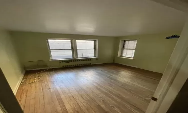 Unfurnished room featuring radiator heating unit and wood-type flooring