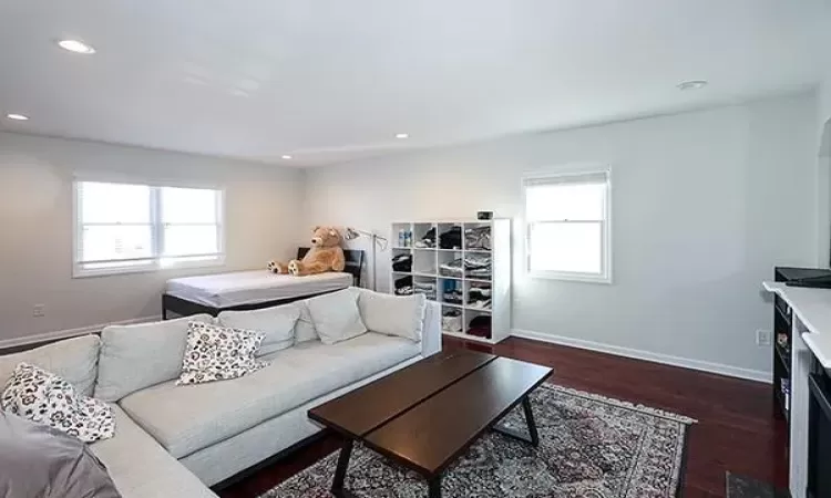 Living room with dark wood-type flooring, recessed lighting, and baseboards