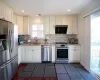 Kitchen with decorative backsplash, light stone counters, stainless steel appliances, a sink, and exhaust hood