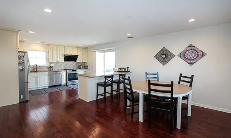 Dining area with dark wood-style floors, plenty of natural light, and recessed lighting