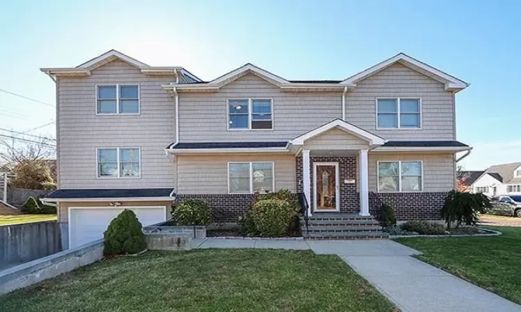 View of front of property featuring an attached garage and a front lawn