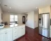 Kitchen with visible vents, dark wood-style floors, light stone counters, stainless steel refrigerator with ice dispenser, and recessed lighting