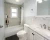 Bathroom with toilet, shower / tub combo, tile walls, and vanity