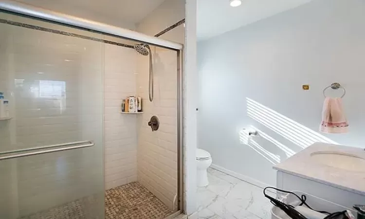 Bathroom with toilet, recessed lighting, vanity, marble finish floor, and a stall shower