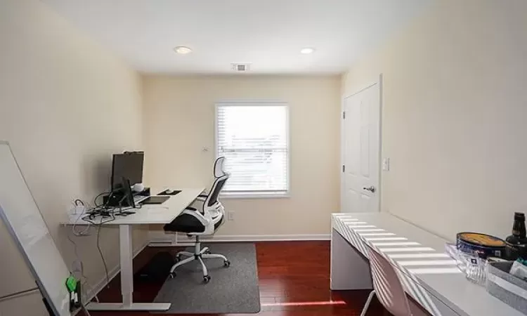 Office space with recessed lighting, visible vents, dark wood finished floors, and baseboards