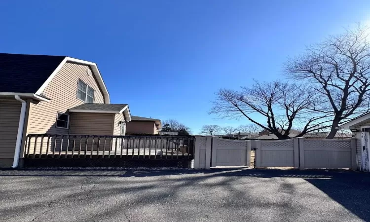 View of home's exterior with a shingled roof and a gate