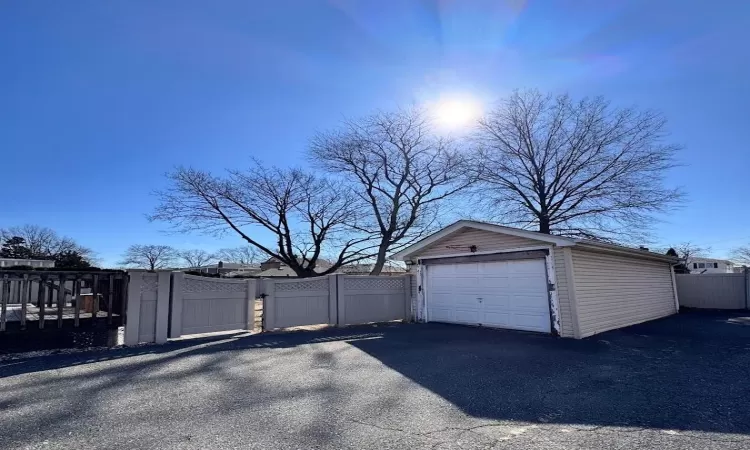 Detached garage featuring driveway, fence, and a gate