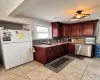 Kitchen with freestanding refrigerator, light tile patterned flooring, a sink, and stainless steel dishwasher