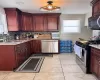 Kitchen featuring stainless steel appliances, light tile patterned flooring, a sink, and decorative backsplash