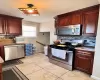 Kitchen featuring light tile patterned floors, dark brown cabinets, stainless steel appliances, and decorative backsplash