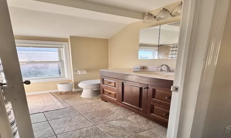 Bathroom with toilet, lofted ceiling, baseboards, and vanity