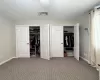 Unfurnished bedroom with carpet, visible vents, baseboards, and two closets