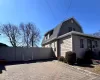 View of property exterior with a shingled roof, a gate, a gambrel roof, and fence