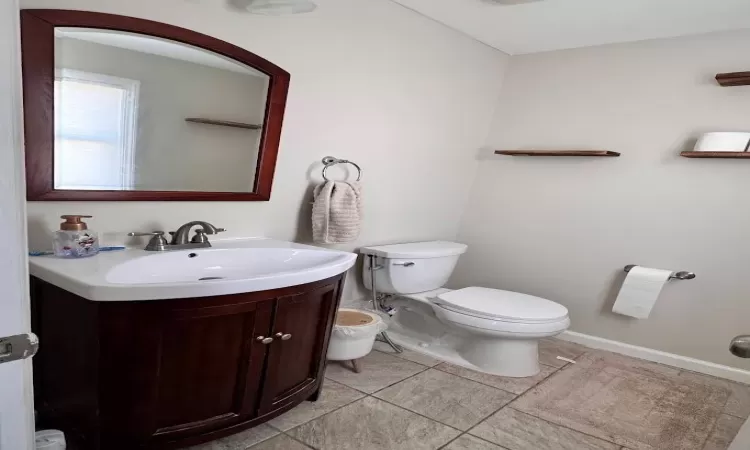 Bathroom with baseboards, vanity, toilet, and tile patterned floors